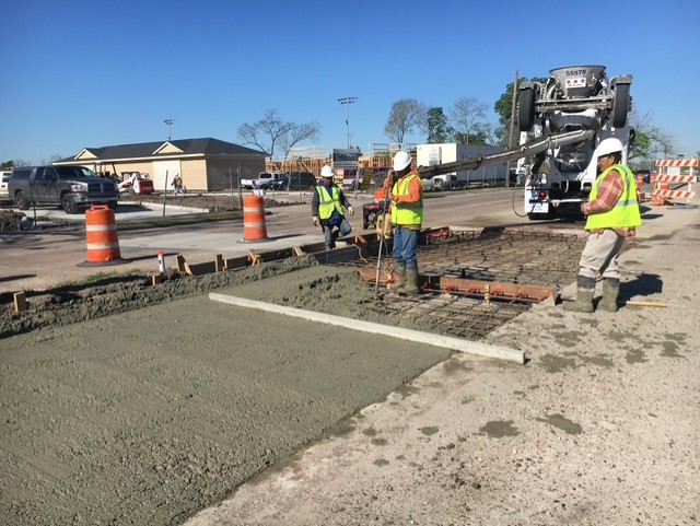 Crew pouring and screeding a reinforced concrete street section
